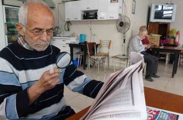 Gazeteleri büyüteçle okuyor 