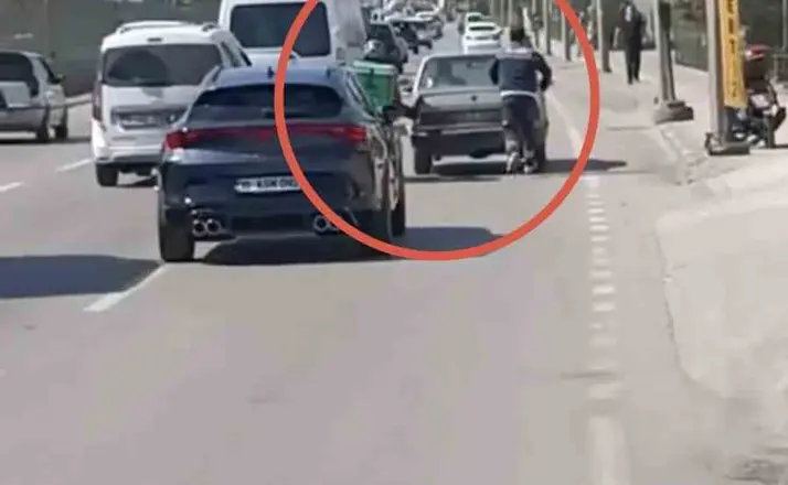 Bursa’da motokuryeden arızalanan otomobili itmek için ilginç yöntem
