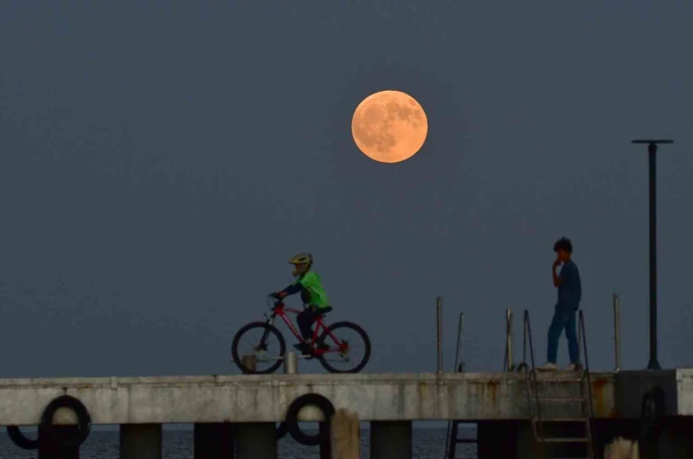Dolunay ile insanların siluetleri aynı karede 