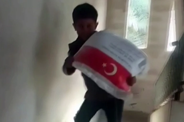Kendi ağırlığı kadar un çuvalını taşıyan Filistinli çocuğun sevinci