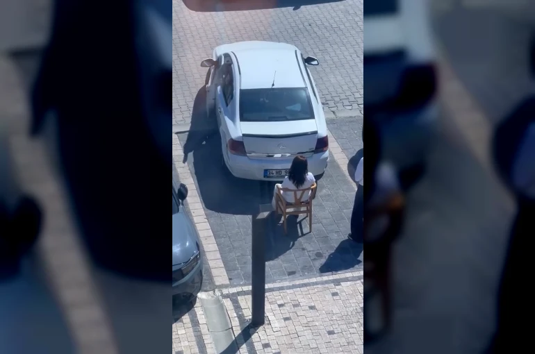 Sandalyeye oturarak kadın sürücünün park etmesini engelledi